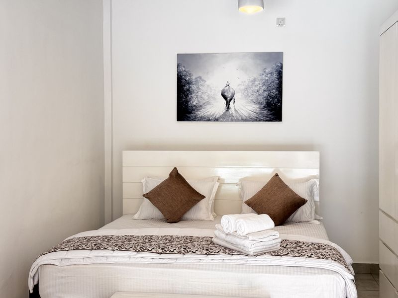 Bedroom one, bright and white, with a queen bed and artwork