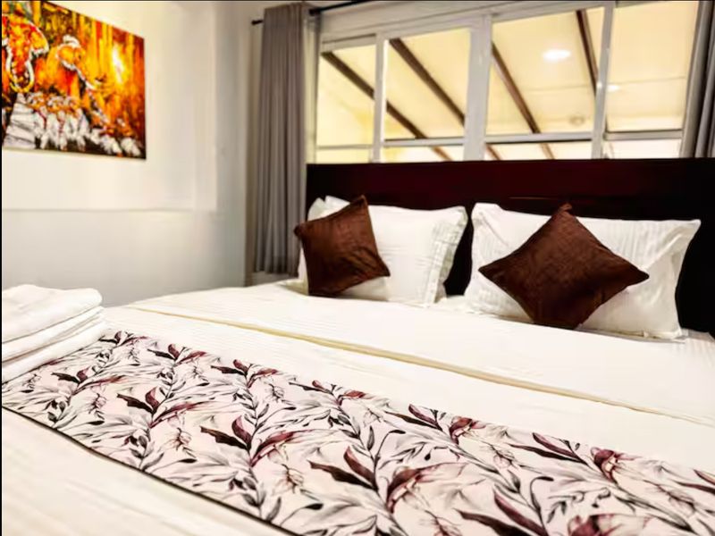Bedroom two, with a queen bed, a wooden headboard and garden windows