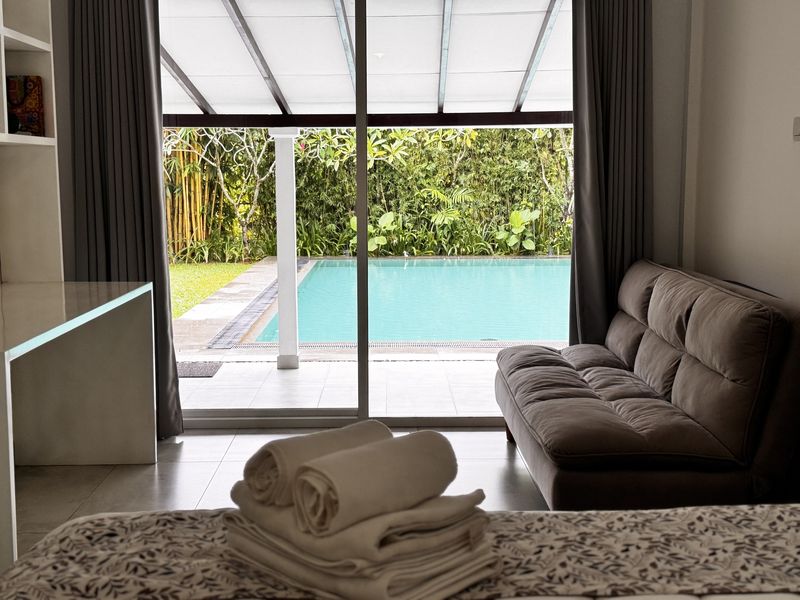 Glass doors from a bedroom open straight onto the pool and garden