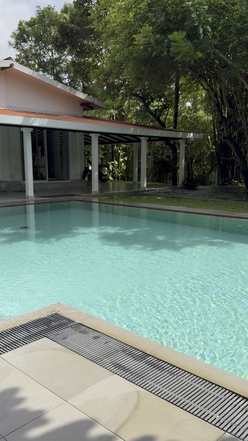 The private pool beside the villa's verandah, shaded by tall trees